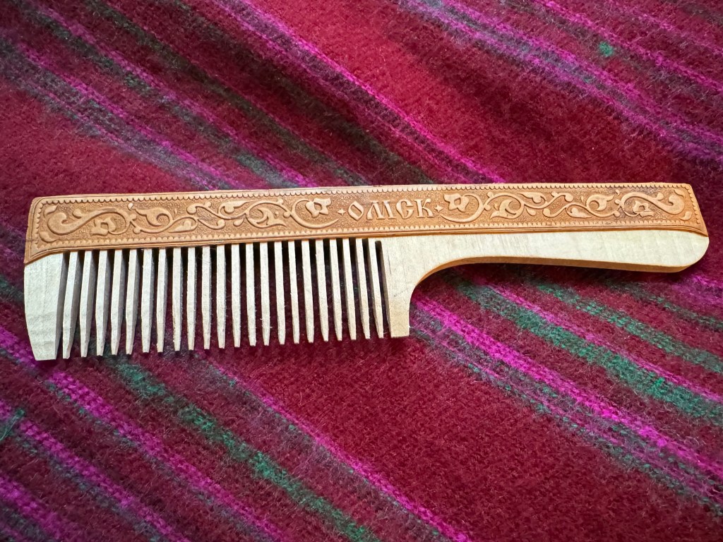 A wooden comb with the handle carved with Omsk and garlands.